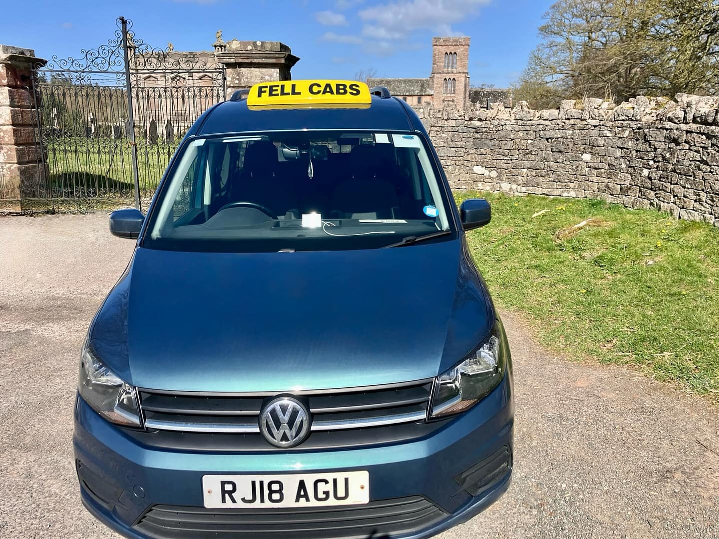 Fell Cabs parked on a sunny day in front of St Michael's Church, Lowther, near Penrith