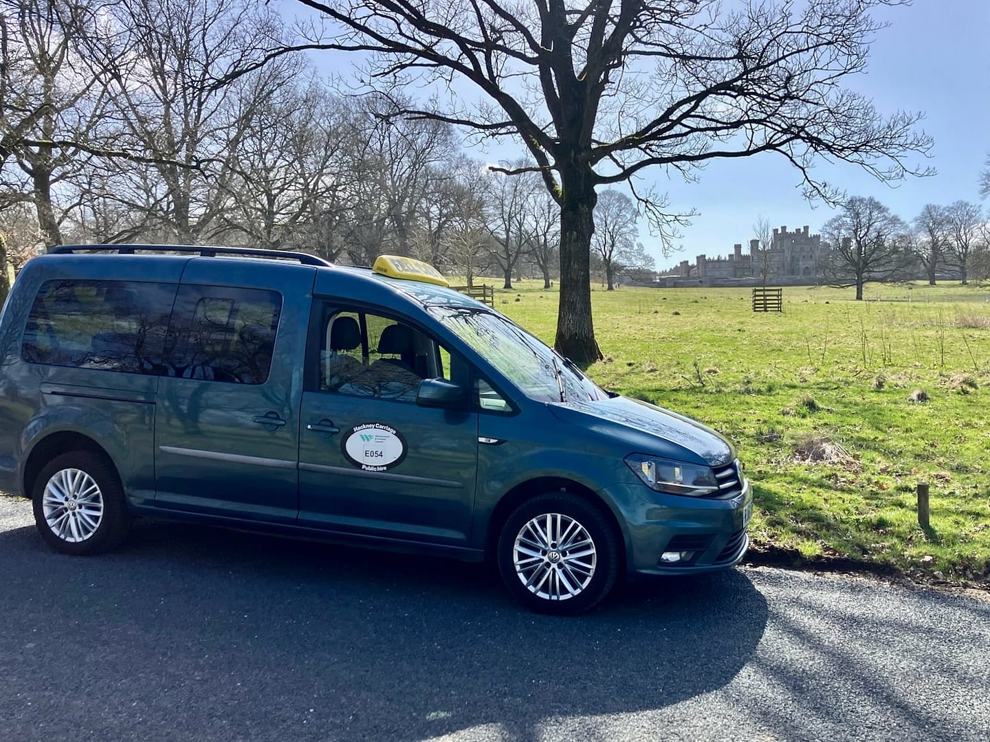Fell Cabs parked on a sunny day with Lowther Castle in the background