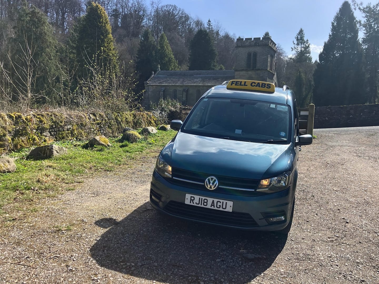 Fell Cabs parked on a sunny day in front of St Peter's Church, Askham, near Penrith